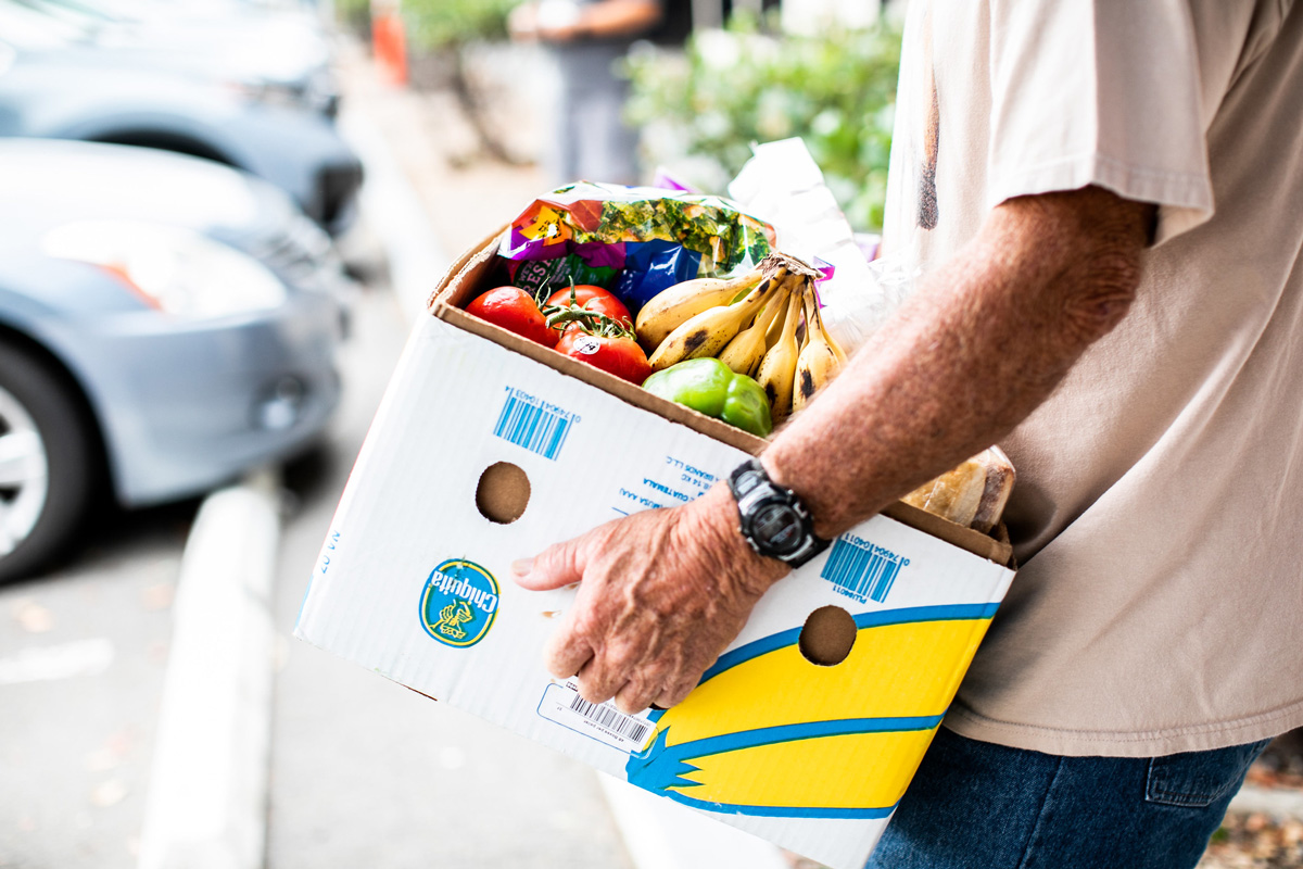 man holding fruit in a cardboard box