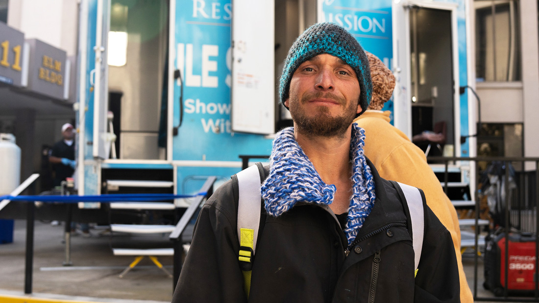 Man with Blue hat in front of a shower trailer